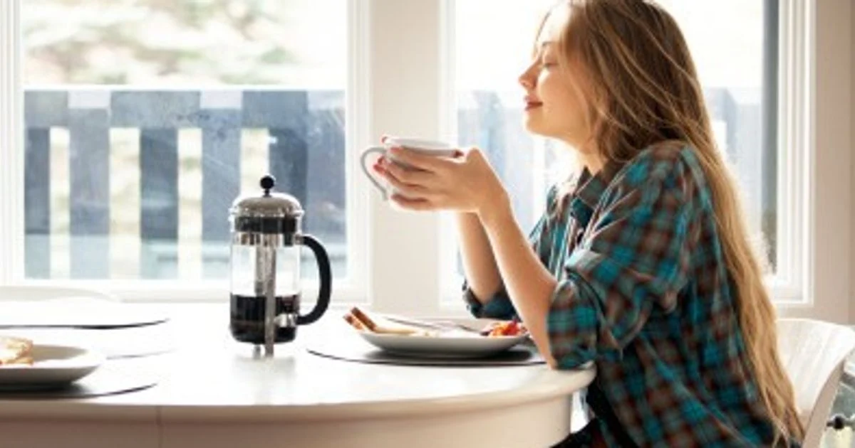 A steaming cup of coffee next to a newspaper and smartphone, symbolizing morning news consumption.