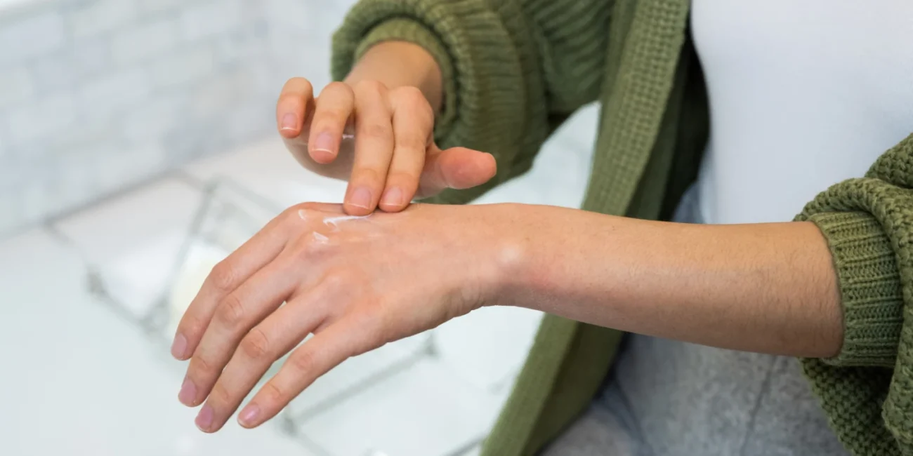 Person applying scar gel cream on skin alongside other scar treatment products.